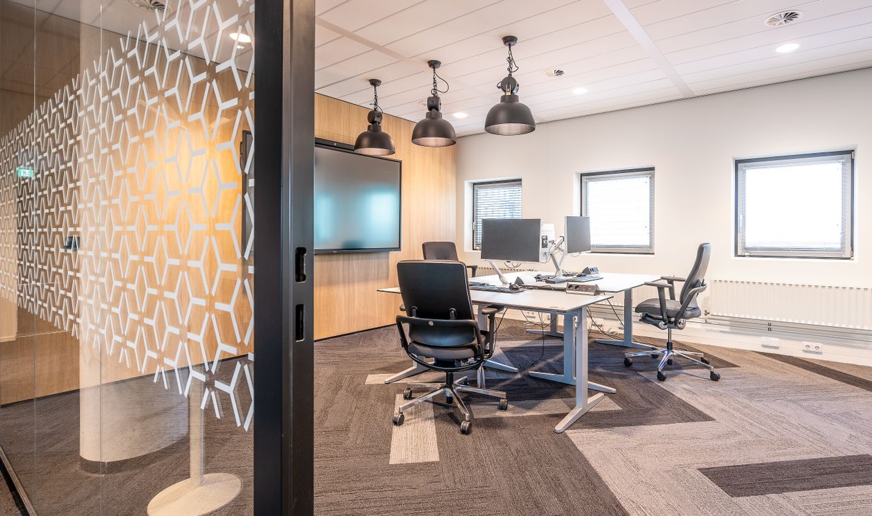 Modern office with glass partitions, coordinated workstations and ceiling lighting